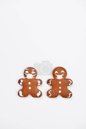 Photo for The hand-made eatable gingerbread little men with face masks on white background - Royalty Free Image