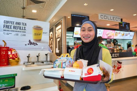 Foto de SINGAPUR - 19 DE ENERO DE 2020: retrato interior del empleado con comida servida en bandeja en el restaurante McDonald 's en Singapur. - Imagen libre de derechos