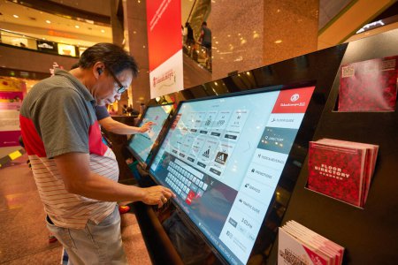 Photo for SINGAPORE - CIRCA JANUARY, 2020: man use interactive touch screen kiosk at Nge Ann City shopping center. - Royalty Free Image