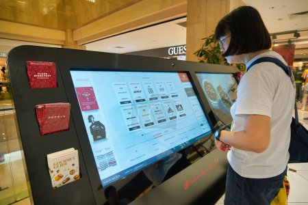 Photo for SINGAPORE - CIRCA JANUARY, 2020: woman use interactive touch screen kiosk at Nge Ann City shopping center. - Royalty Free Image