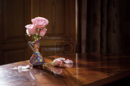 Foto de Bodegón con rosa en jarrón sobre mesa de madera - Imagen libre de derechos