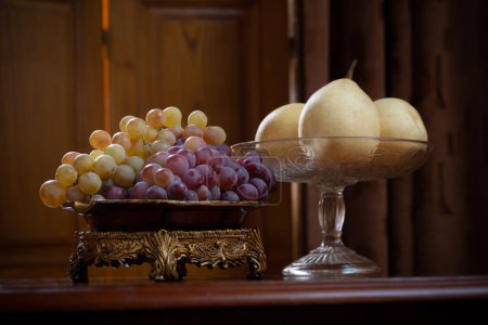 Photo for Still life with plates full of grapes and pears on wooden background - Royalty Free Image