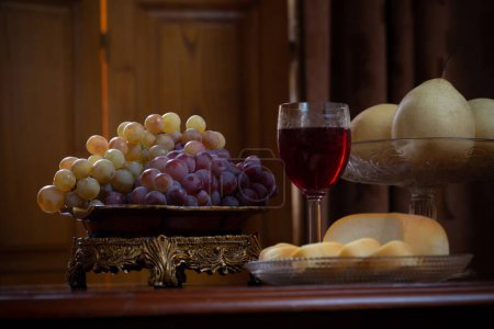 Foto de Bodegón con frutas y queso y copa de vid roja sobre fondo de madera - Imagen libre de derechos