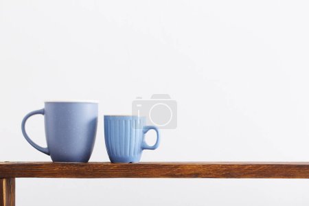 Foto de Dos tazas azules en estante de madera sobre fondo blanco - Imagen libre de derechos