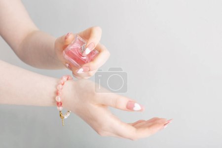 Téléchargez les photos : Mains féminines avec flacon de parfum sur fond blanc - en image libre de droit