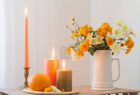 Téléchargez les photos : Fleurs d'automne avec des bougies brûlantes et des citrouilles sur une étagère en bois vintage - en image libre de droit