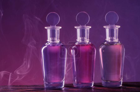 Foto de Botellas con poción mágica en humo sobre fondo púrpura - Imagen libre de derechos