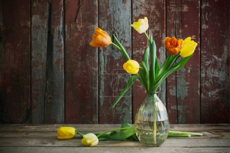 Foto de Tulipanes en jarrón de vidrio sobre fondo de madera viejo - Imagen libre de derechos