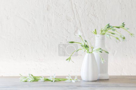 Téléchargez les photos : Fleurs blanches dans un vase sur fond vieux mur blanc - en image libre de droit