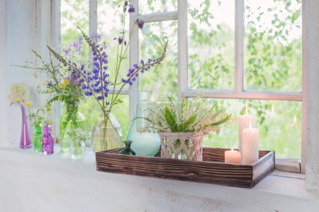 Téléchargez les photos : Fleurs avec des bougies allumées sur le rebord de la fenêtre blanche - en image libre de droit