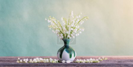 Téléchargez les photos : Lys de la vallée en vase sur table en bois sur fond vert - en image libre de droit