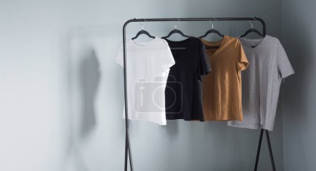 Photo for T-shirts of neutral colors on  black hanger against  gray wall - Royalty Free Image