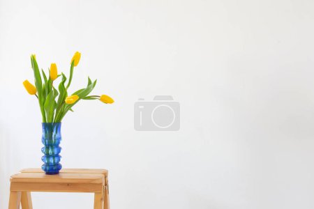 Foto de Tulipanes amarillos en jarrón de cristal azul sobre fondo blanco - Imagen libre de derechos