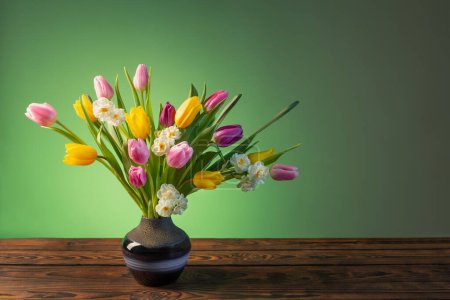 Foto de Flores de primavera en jarrón de cerámica azul sobre mesa de madera - Imagen libre de derechos