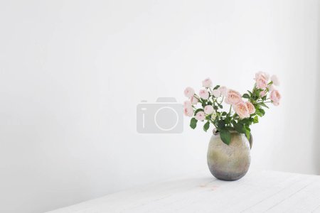 Bouquet of peony roses in ceramic jug on white background