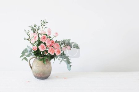 Foto de Ramo de rosas de peonía en jarra de cerámica sobre fondo blanco - Imagen libre de derechos