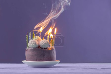 Foto de Pastel de cumpleaños púrpura con velas encendidas sobre fondo violeta - Imagen libre de derechos