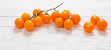 Foto de Tomates naranja cereza sobre fondo de madera blanca - Imagen libre de derechos