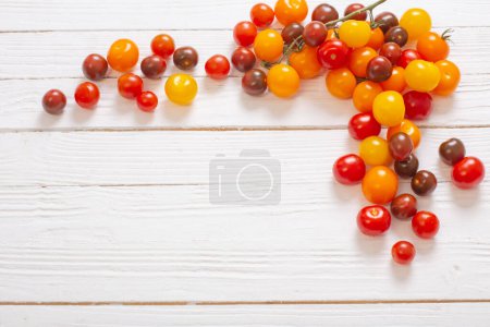 Téléchargez les photos : Diverses tomates sur fond de bois blanc - en image libre de droit