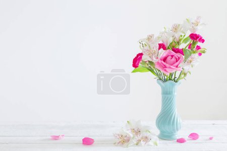 Pink and white flowers in blue vase on white background