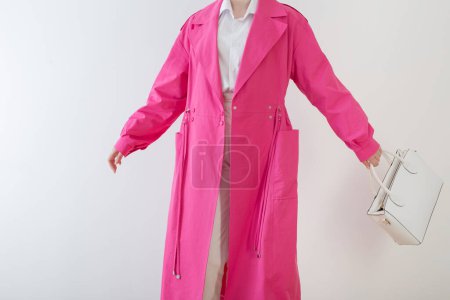 Foto de Mujer en abrigo de trinchera rosa con bolso blanco - Imagen libre de derechos