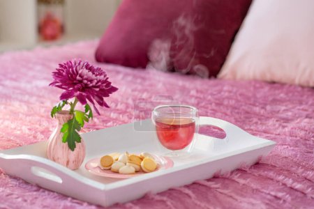 Photo for Red tea in thermo glass with flowers in modern bedroom - Royalty Free Image