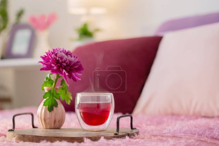 Foto de Té rojo en vidrio termo con flores en dormitorio moderno - Imagen libre de derechos