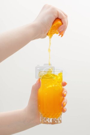 Téléchargez les photos : Main avec du jus d'orange sur fond blanc - en image libre de droit