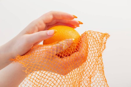 Téléchargez les photos : Main féminine avec sac à ficelle orange et synthétique - en image libre de droit