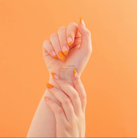 weibliche Hand mit Maniküre auf orangefarbenem Hintergrund