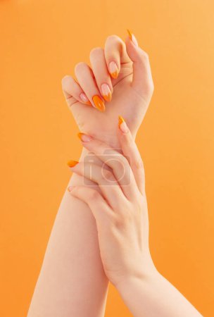 Téléchargez les photos : Main féminine avec manucure sur fond orange - en image libre de droit