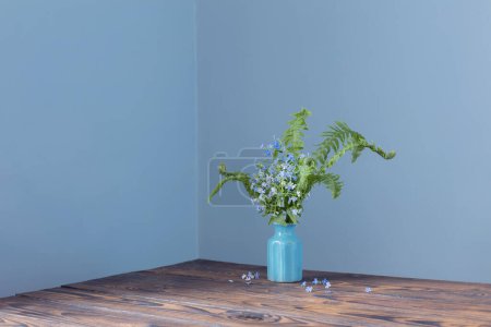 Photo for Wild flowers in vase on background blue wall - Royalty Free Image