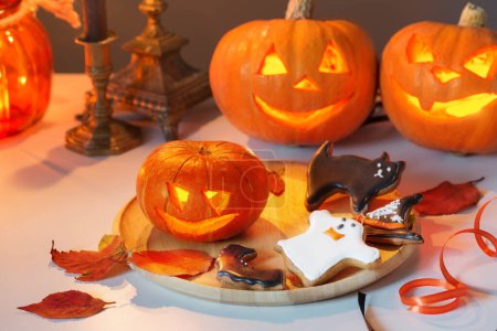 Téléchargez les photos : Citrouilles halloween avec des bougies allumées sur table blanche - en image libre de droit