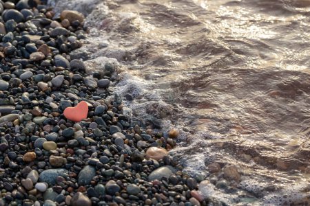 Photo for Red stone in  shape of heart on  beach by  sea - Royalty Free Image