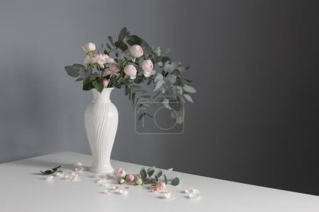Téléchargez les photos : Bouquet de roses roses en vase blanc céramique sur fond mural gris - en image libre de droit