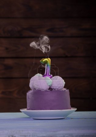 Foto de Pastel de cumpleaños púrpura con vela encendida sobre fondo de madera - Imagen libre de derechos