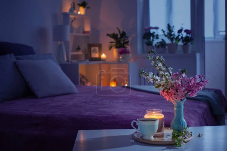Foto de Acogedor dormitorio por la noche con flores y té - Imagen libre de derechos