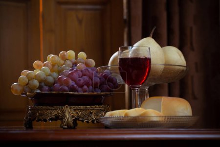 Foto de Bodegón con frutas y queso y copa de vid roja sobre fondo de madera - Imagen libre de derechos
