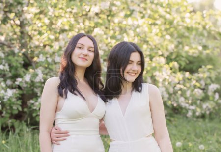 Photo for Two young girls in white dress on background flowering apple tree - Royalty Free Image