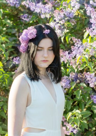 Téléchargez les photos : Jeune fille avec lilas en fleurs dans la lumière du soleil - en image libre de droit