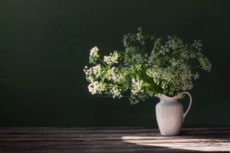 Téléchargez les photos : Fleurs sauvages blanches en cruche sur fond vert mur - en image libre de droit