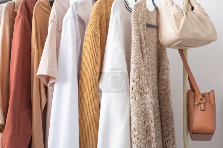 Photo for Female autumn clothes on hangers  in  white room - Royalty Free Image