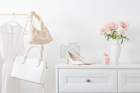 Foto de Vestidor blanco con ropa y flores en habitación blanca - Imagen libre de derechos