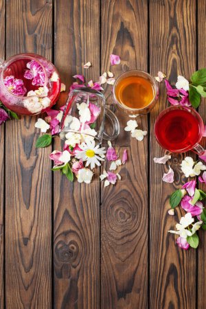 Foto de Varios tés con hierbas y flores en una mesa de madera oscura, vista superior - Imagen libre de derechos