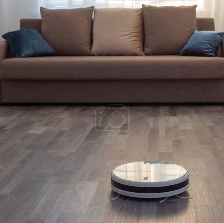 Foto de Aspiradora robot en el suelo en la sala de estar - Imagen libre de derechos