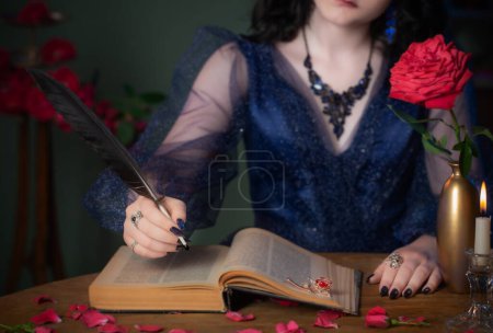 Téléchargez les photos : Jeune belle femme en robe vintage bleue avec livre sur table dans la chambre noire - en image libre de droit