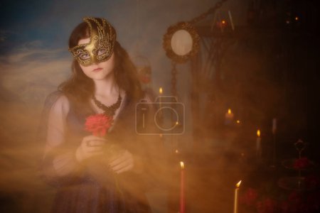 Téléchargez les photos : Jeune belle femme en masque doré et robe vintage bleue dans la chambre noire - en image libre de droit