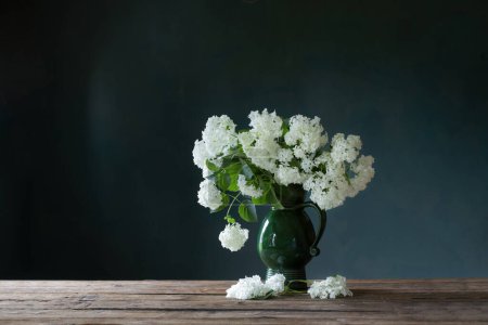 Téléchargez les photos : Hydragea blanc en cruche vintage sur table en bois sur fond mur sombre - en image libre de droit