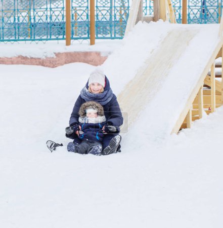 Téléchargez les photos : Maman et petit enfant sur l'aire de jeux d'hiver - en image libre de droit
