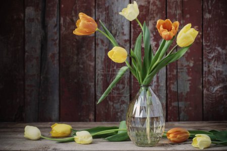 Téléchargez les photos : Tulipes dans un vase en verre sur un vieux fond en bois - en image libre de droit